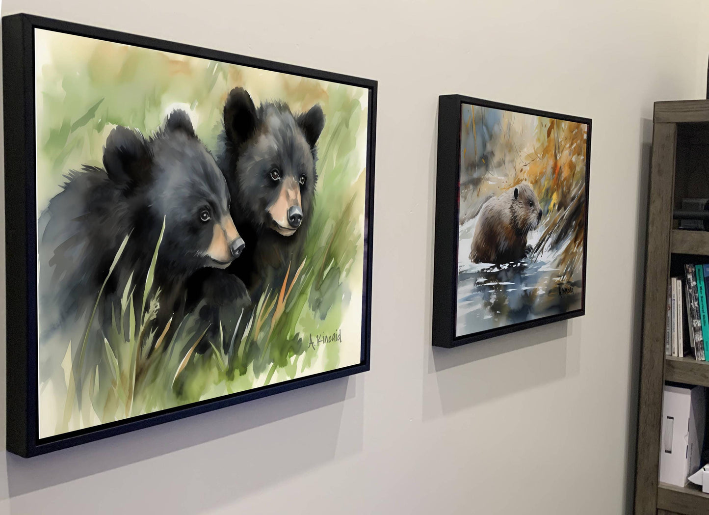 two framed paintings of black bears, one depicting a bear standing in tall grass and the other showing a bear in the water.