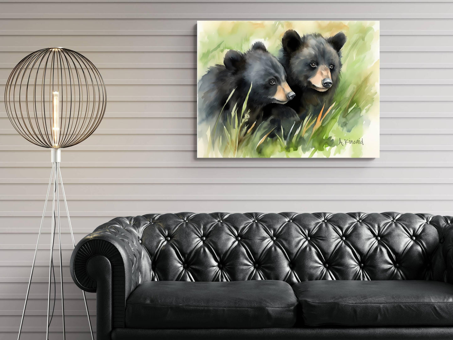 a black leather couch in a living room setting, with a painting of two black bears in the grass hanging on the wall above it.