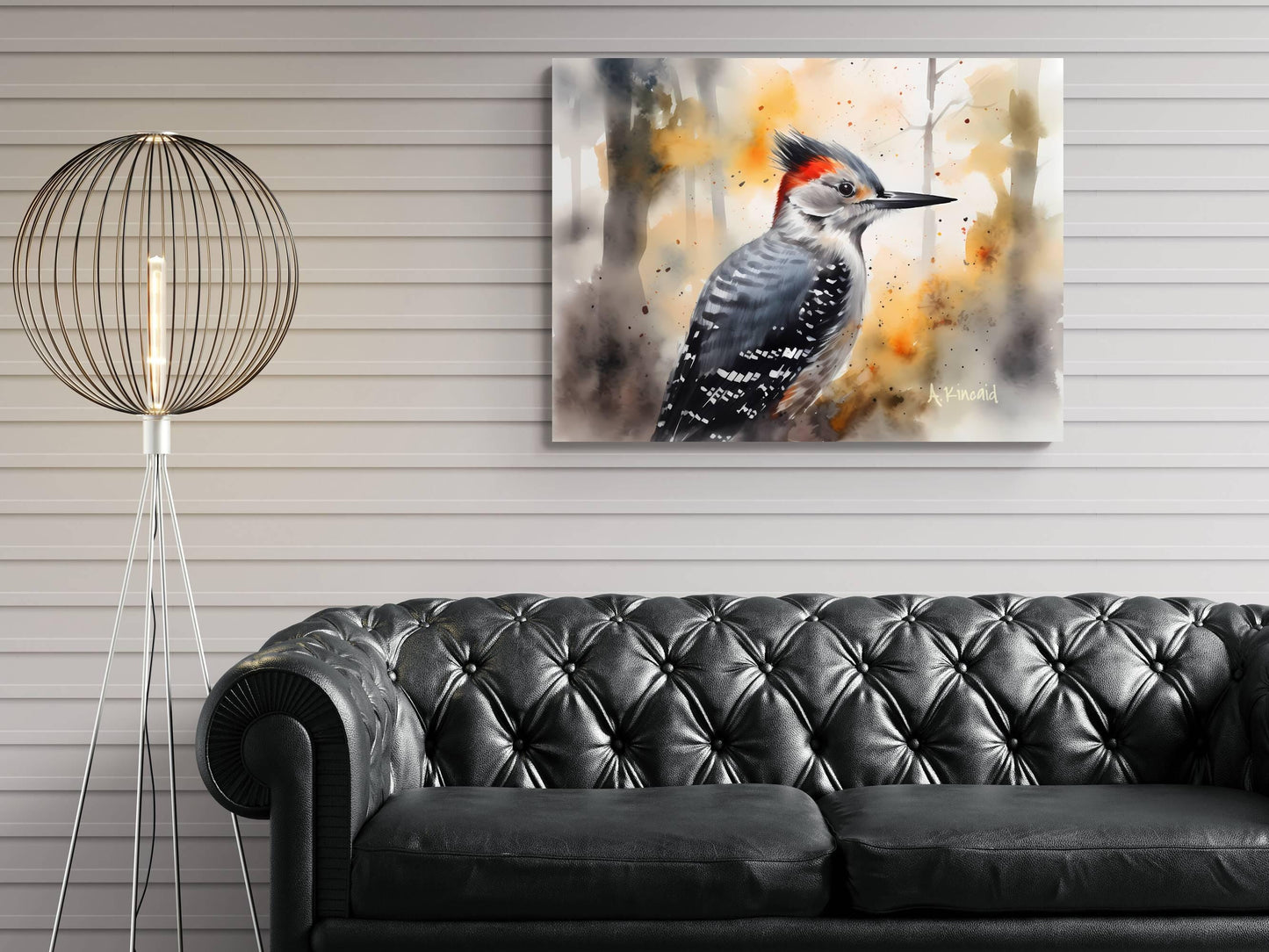 a black leather sofa in a living room setting, with a painting of a woodpecker hanging on the wall above it.