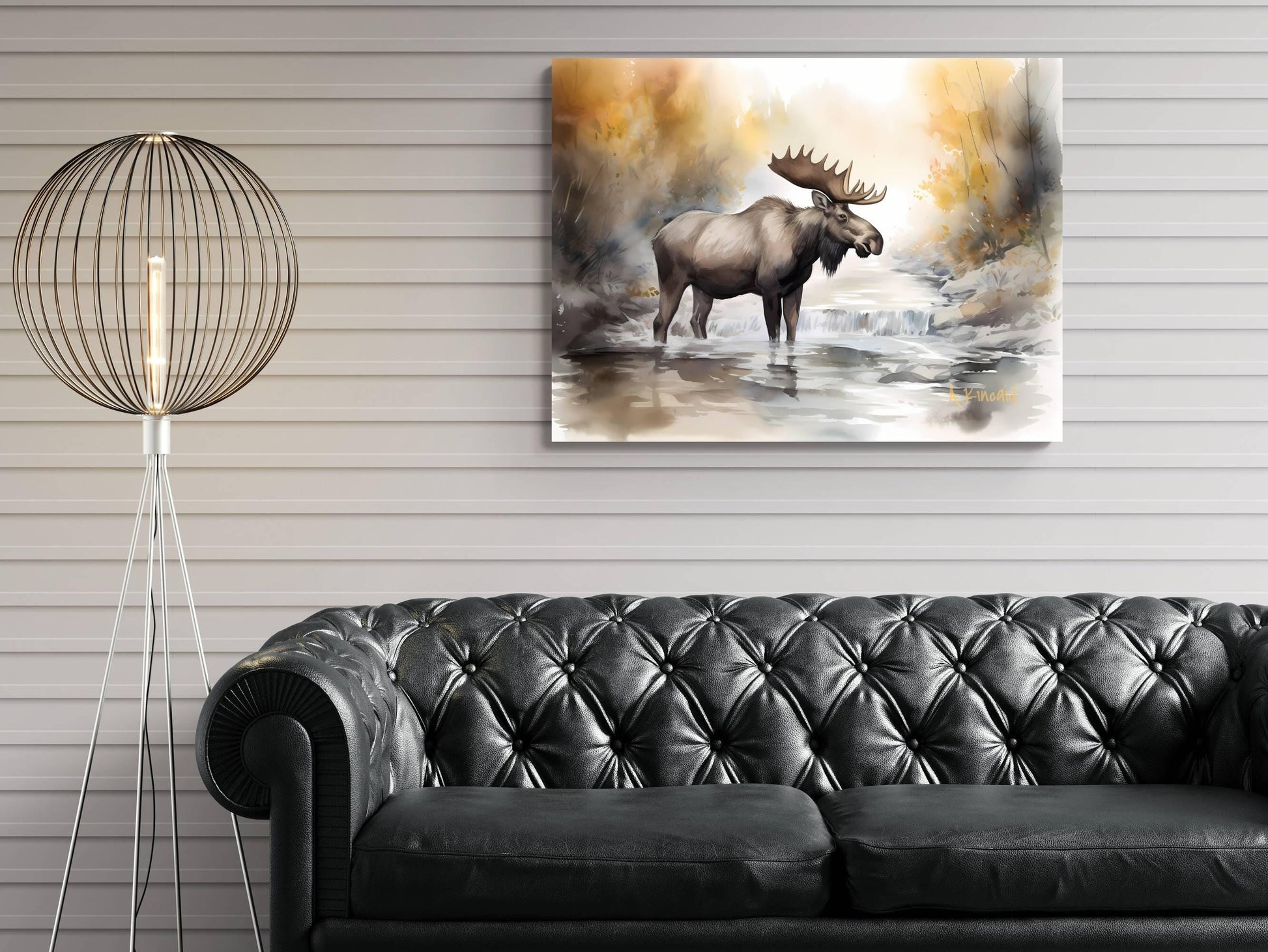 a large painting of a moose standing in a river, hanging on a wall above a black leather couch.